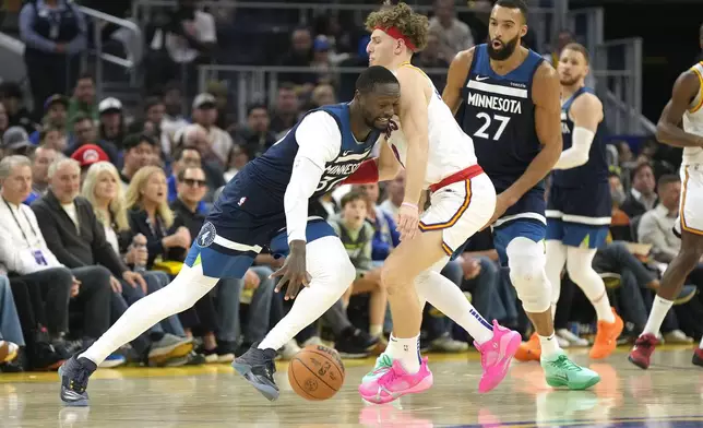 Minnesota Timberwolves forward Julius Randle, left, dribbles around Golden State Warriors guard Brandin Podziemski, second from left, during the first half of an NBA basketball game in San Francisco, Sunday Dec. 8, 2024. (AP Photo/Tony Avelar)
