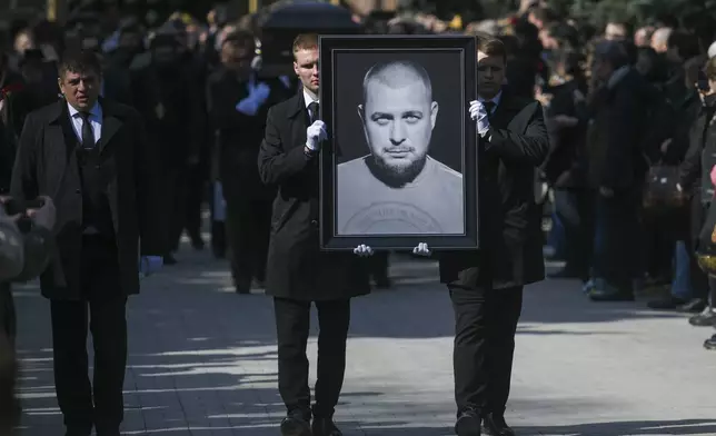 FILE - Cemetery workers carry a portrait of slain Russian military blogger Vladlen Tatarsky during a funeral at the Troyekurovskoye Cemetery in Moscow, Russia, on April 8, 2023. (Anton Velikzhanin, M24/Moscow News Agency via AP, File)