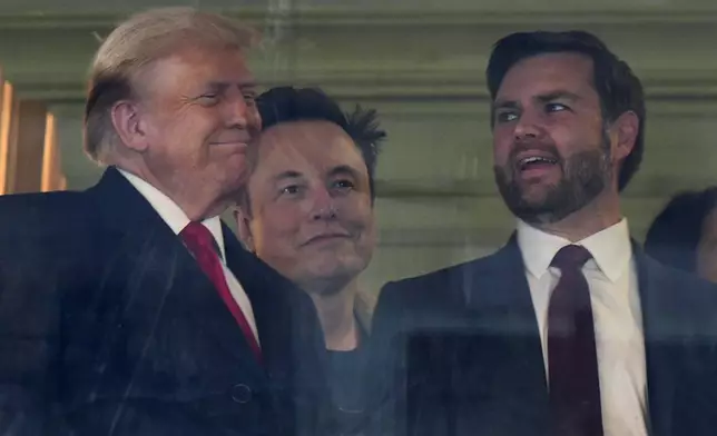 In this picture taken through a window, President-elect Donald Trump, from left, Trump's pick for the planned Department of Government Efficiency Elon Musk and Vice President-elect JD Vance attend the NCAA college football game between Army and Navy at Northwest Stadium in Landover, Md., Saturday, Dec. 14, 2024. (AP Photo/Stephanie Scarbrough)