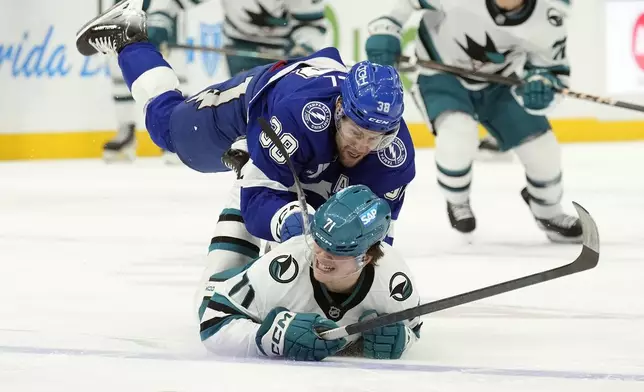 Tampa Bay Lightning left wing Brandon Hagel (38) knocks down San Jose Sharks center Macklin Celebrini (71) during the first period of an NHL hockey game Thursday, Dec. 5, 2024, in Tampa, Fla. (AP Photo/Chris O'Meara)