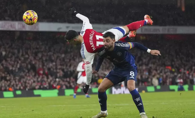 Arsenal's Gabriel Martinelli goes over Manchester United's Bruno Fernandes as they challenge for the ball during the English Premier League soccer match between Arsenal and Manchester United at Emirates stadium in London, Wednesday, Dec. 4, 2024. (AP Photo/Kirsty Wigglesworth)