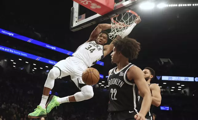 Milwaukee Bucks' Giannis Antetokounmpo dunks the ball past Brooklyn Nets' Jalen Wilson and Ben Simmons during the first half of an NBA basketball game, Sunday, Dec. 8, 2024, in New York. (AP Photo/Heather Khalifa)