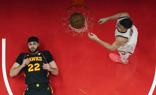 Denver Nuggets guard Christian Braun (0) scores as Atlanta Hawks forward Larry Nance Jr. (22) looks during the first half of an NBA basketball game, Sunday, Dec. 8, 2024, in Atlanta. (AP Photo/John Bazemore)