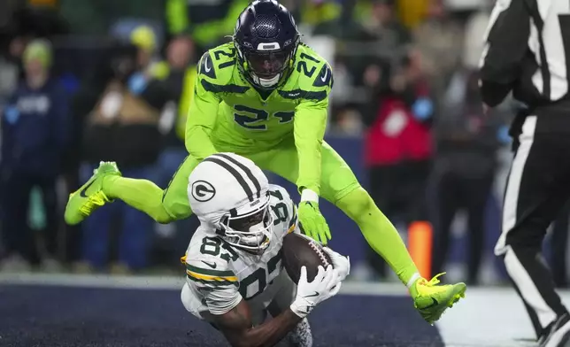 Green Bay Packers' Romeo Doubs catches a touchdown pass in front of Seattle Seahawks' Devon Witherspoon during the second half of an NFL football game Sunday, Dec. 15, 2024, in Seattle. (AP Photo/Lindsey Wasson)