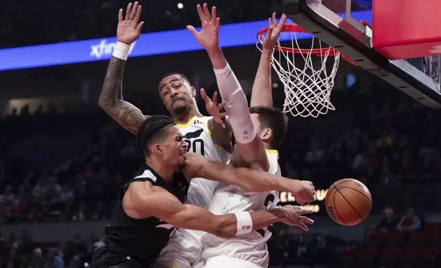 Portland Trail Blazers forward Toumani Camara, left, passes the ball around the Utah Jazz defense during the first half of an NBA basketball game Friday, Dec. 6, 2024, in Portland, Ore. (AP Photo/Jenny Kane)