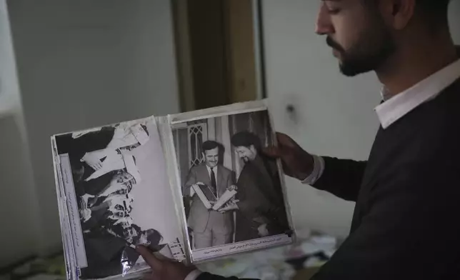 FILE.- A man shows old pictures of the late Syrian President Hafez Assad as people search for belongings in the ransacked private residence of Syrian President Bashar Assad in Damascus, Syria, on Sunday, Dec. 8, 2024. (AP Photo/Ghaith Alsayed,File)