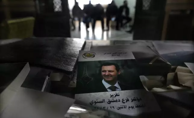 FILE.- A cover showing ousted Syrian President Bashar Assad, seen on a desk at the Baath party headquarter, as former army soldiers, background, wait to register their names with Syrian rebels as part of an "identification and reconciliation" process in Damascus, Syria, Monday, Dec. 23, 2024. (AP Photo/Hussein Malla,File)