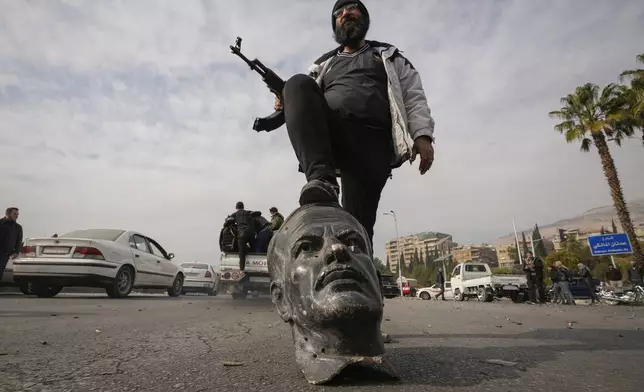 FILE.- An opposition fighter steps on a broken bust of the late Syrian President Hafez Assad in Damascus, Syria, Sunday Dec. 8, 2024. (AP Photo/Hussein Malla,File)