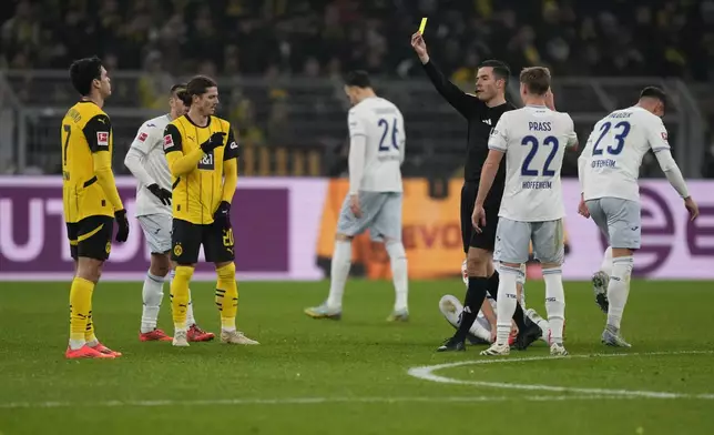 The referee shows a yellow card to Dortmund's Giovanni Reyna, left, during the German Bundesliga soccer match between Borussia Dortmund and TSG Hoffenheim at the Signal-Iduna Park in Dortmund, Germany, Sunday, Dec. 15 2024. (AP Photo/Martin Meissner)