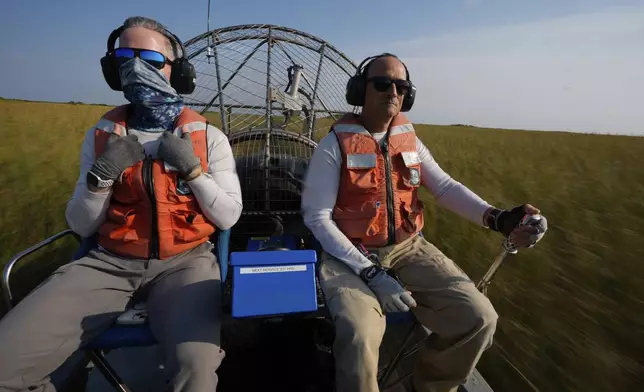 Florida International University professor John Kominoski, left, and research specialist Rafael Travieso travel by airboat through Shark River Slough on their way to collect water samples and maintain automatic sampling equipment in Florida's Everglades National Park, Tuesday, May 14, 2024. (AP Photo/Rebecca Blackwell)