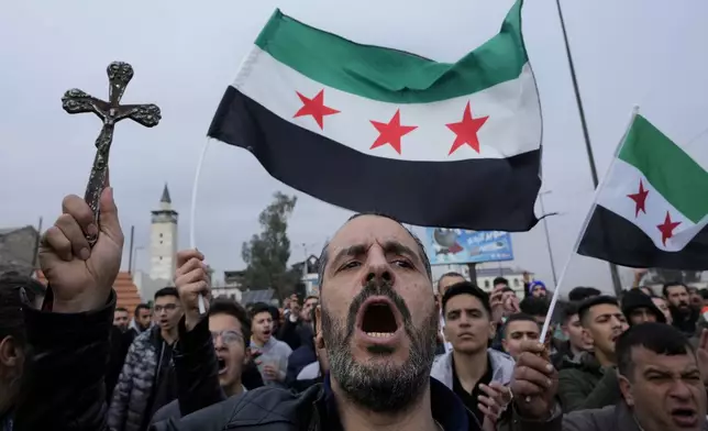 A Syrian Christian man holds up a cross and shouts slogans in Damascus, Syria, Tuesday, Dec. 24, 2024, during a protest march after a Christmas tree was set on fire in Hamah city on Sunday. (AP Photo/Hussein Malla)