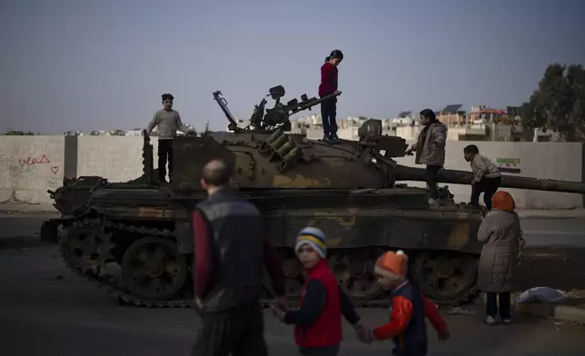 Children on the top of an ousted Syrian government forces tank that was left on a street in an Alawite neighbourhood, in Homs, Syria, Thursday, Dec. 26, 2024. (AP Photo/Leo Correa)