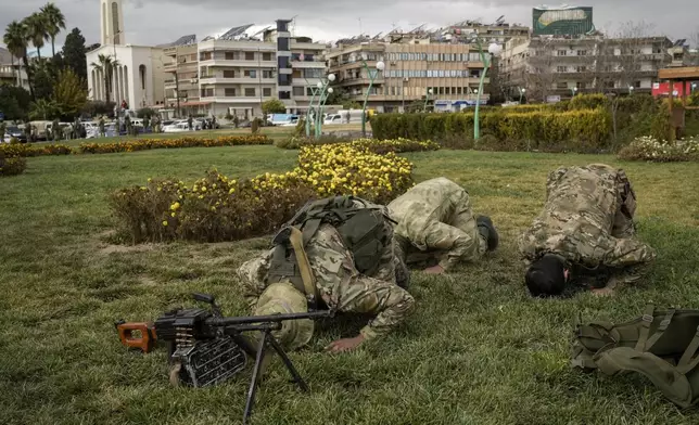 Members of the armed forces and former rebels, who overthrew Bashar Assad's government and now serve in the new Syrian government, pray before a military parade in downtown Damascus, Syria, Friday, Dec. 27, 2024. (AP Photo/Leo Correa)