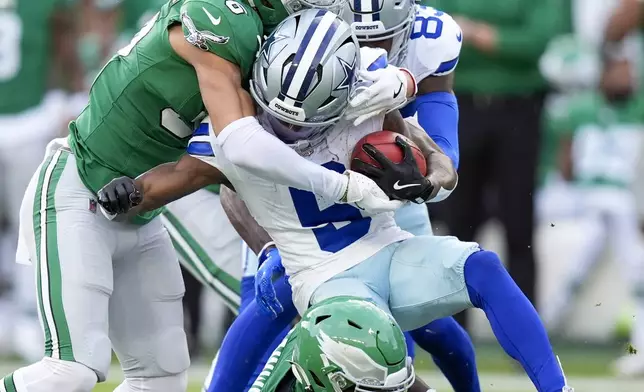 Dallas Cowboys' KaVontae Turpin, center, is tackled by Philadelphia Eagles' Tristin McCollum, top and Kenneth Gainwell (14) on a kickoff return during the first half of an NFL football game, Sunday, Dec. 29, 2024, in Philadelphia. (AP Photo/Chris Szagola)