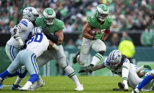 Philadelphia Eagles running back Saquon Barkley, center, leaps as Dallas Cowboys linebacker Marist Liufau tries to trip him up during the second half of an NFL football game, Sunday, Dec. 29, 2024, in Philadelphia. (AP Photo/Matt Slocum)