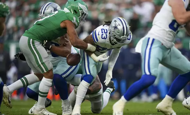 Philadelphia Eagles linebacker Nolan Smith Jr., left, punches the ball out of the hands of Dallas Cowboys running back Rico Dowdle (23) during the second half of an NFL football game, Sunday, Dec. 29, 2024, in Philadelphia. The Eagles recovered the fumble. (AP Photo/Matt Slocum)