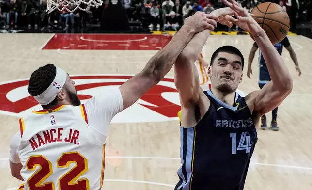 Atlanta Hawks forward Larry Nance Jr. (22) blocks a shot by Memphis Grizzlies center Zach Edey (14) during the first half of an NBA basketball game, Saturday, Dec. 21, 2024, in Atlanta. (AP Photo/Mike Stewart)