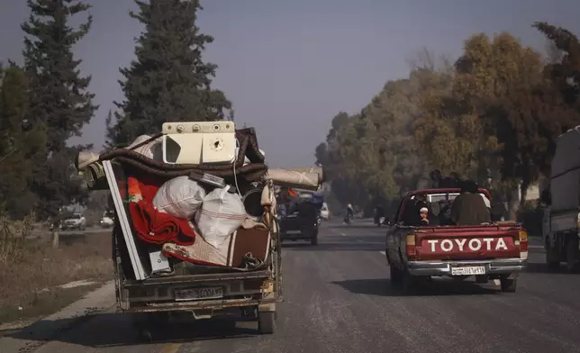 Residents leave the city carrying their belongings in Hama, Syria, Friday Dec. 6, 2024.(AP Photo/Omar Albam)