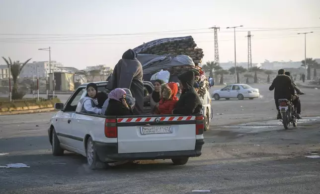 Residents leave the city carrying their belongings in Hama, Syria, Friday Dec. 6, 2024.(AP Photo/Omar Albam)