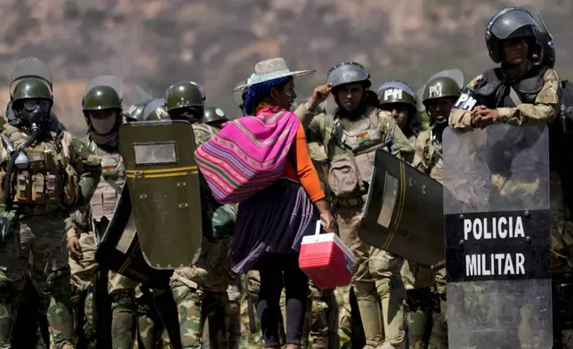 FILE - A vendor offers ice cream for sale to military police after they removed roadblocks set up by supporters of former President Evo Morales to prevent him from facing a criminal investigation over allegations of abuse of a minor while in office, in Parotani, Bolivia, Nov. 1, 2024. (AP Photo/Juan Karita, File)