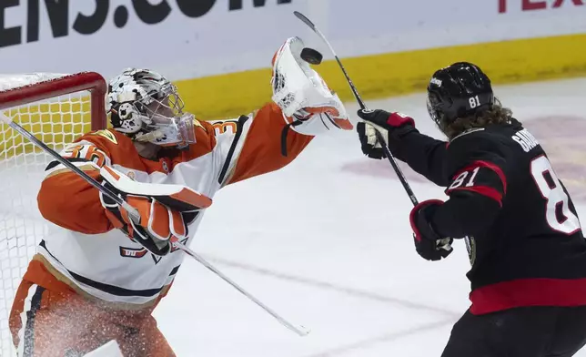 Ottawa Senators' Adam Gaudette takes a swing at the puck as Anaheim Ducks goaltender John Gibson grabs it with his glove during the third period of an NHL hockey game, Wednesday, Dec. 11, 2024 in Ottawa, Ontario. (Adrian Wyld/The Canadian Press via AP)