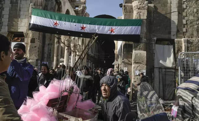 A Syrian "revolutionary" flag hangs at the entrance of the Umayyad Mosque ahead of Friday prayers in Damascus, Syria, Friday Dec. 20, 2024. 2024.(AP Photo/Leo Correa)