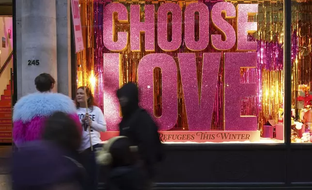 Christmas shoppers pass a sign in a shop window 'Choose Love' in central London, Friday, Dec. 13, 2024, Britain's economy unexpectedly shrank by 0.1 percent in October, The Office for National Statistics stated in figures released Friday. (AP Photo/Alberto Pezzali)