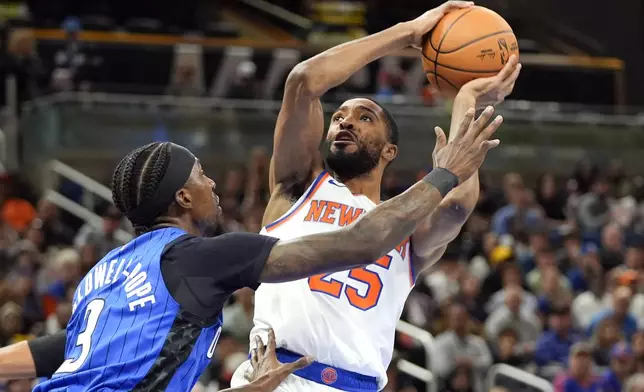 New York Knicks forward Mikal Bridges, right, takes a shot over Orlando Magic guard Kentavious Caldwell-Pope (3) during the first half of an NBA basketball game, Friday, Dec. 27, 2024, in Orlando, Fla. (AP Photo/John Raoux)