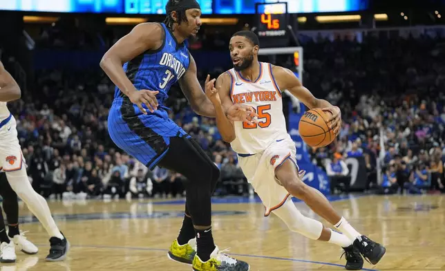 New York Knicks forward Mikal Bridges, right, drives past Orlando Magic guard Kentavious Caldwell-Pope (3) during the first half of an NBA basketball game, Friday, Dec. 27, 2024, in Orlando, Fla. (AP Photo/John Raoux)