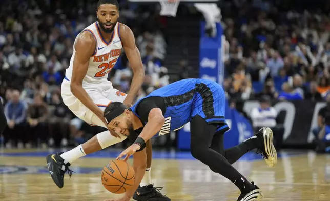 Orlando Magic guard Jalen Suggs slips as he tries to drive past New York Knicks forward Mikal Bridges (25) during the second half of an NBA basketball game, Friday, Dec. 27, 2024, in Orlando, Fla. (AP Photo/John Raoux)