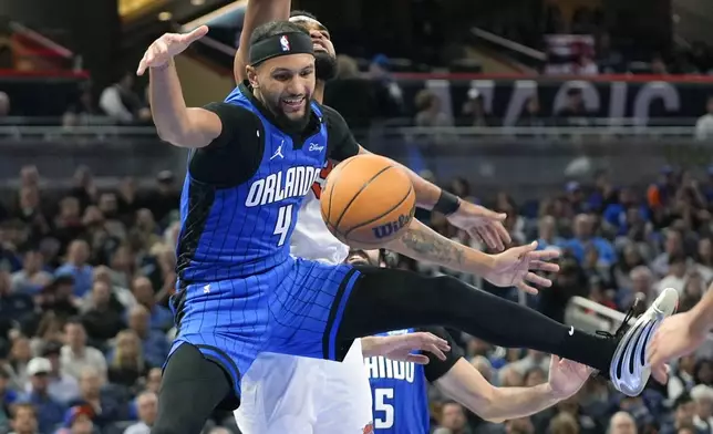 Orlando Magic guard Jalen Suggs (4) loses control of the ball while going up for a shot against New York Knicks center Karl-Anthony Towns during the second half of an NBA basketball game, Friday, Dec. 27, 2024, in Orlando, Fla. (AP Photo/John Raoux)