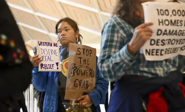 A protestor holds a sign as the Republican-dominated North Carolina House convened to complete the override of Gov. Cooper's veto, Wednesday, Dec. 11, 2024, in Raleigh, N.C. (AP Photo/Matt Kelley)