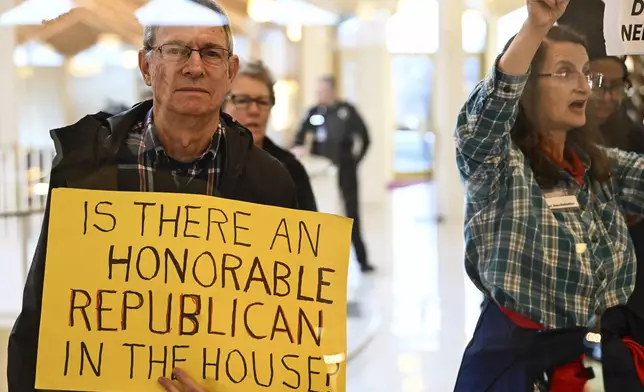 A protester holds a sign as the Republican-dominated North Carolina House convened to complete the override of Democratic Gov. Roy Cooper's veto of a bill that aims to weaken the powers of Cooper's soon-to-be successor and other Democratic statewide winners in the Nov. 5 elections, Wednesday, Dec. 11, 2024, in Raleigh, N.C. (AP Photo/Matt Kelley)