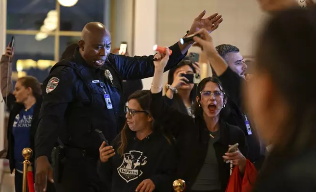 A general assembly police officer escorts protestors after the Republican-dominated North Carolina House convened and completed the override of Democratic Gov. Roy Cooper's veto of a bill that aims to weaken the powers of Cooper's soon-to-be successor and other Democratic statewide winners in the Nov. 5 elections, Wednesday, Dec. 11, 2024, in Raleigh, N.C. (AP Photo/Matt Kelley)