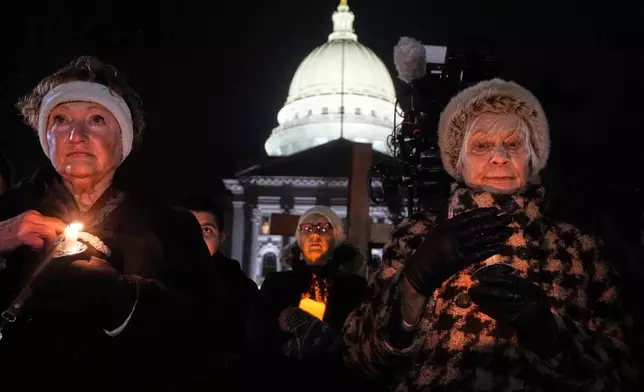 Supporters hold candles during a candlelight vigil Tuesday, Dec. 17, 2024, outside the Wisconsin Capitol in Madison, Wis., following a shooting at the Abundant Life Christian School on Monday, Dec. 16. (AP Photo/Morry Gash)