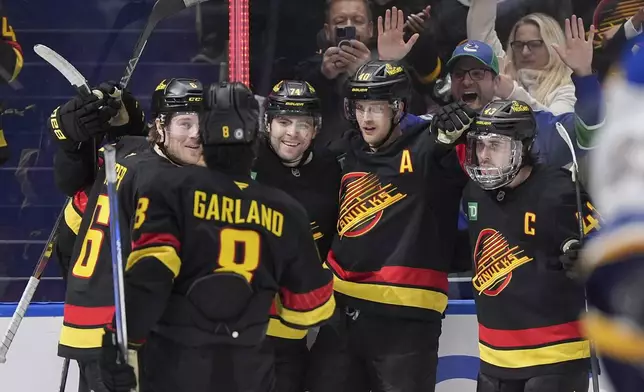 Vancouver Canucks' Jake DeBrusk (74), Brock Boeser (6), Elias Pettersson (40), Quinn Hughes (43) and Conor Garland (8) celebrate DeBrusk's goal against the St. Louis Blues during the third period of an NHL hockey game in Vancouver, Tuesday, Dec. 10, 2024. (Darryl Dyck/The Canadian Press via AP)