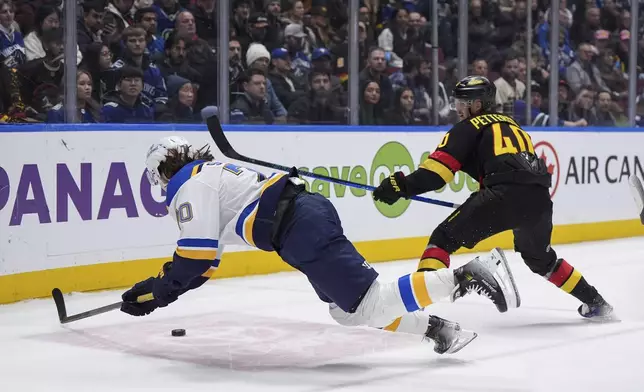 St. Louis Blues' Brandon Saad, front left, falls while vying for the puck against Vancouver Canucks' Elias Pettersson during the third period of an NHL hockey game in Vancouver, Tuesday, Dec. 10, 2024. (Darryl Dyck/The Canadian Press via AP)