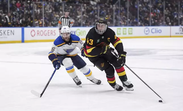 Vancouver Canucks' Quinn Hughes (43) skates with the puck while being followed by St. Louis Blues' Nathan Walker (26) during the third period of an NHL hockey game in Vancouver, Tuesday, Dec. 10, 2024. (Darryl Dyck/The Canadian Press via AP)