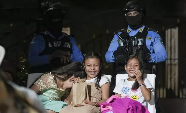 State-assigned bodyguards stand guard over Julia Lopez Peña, center, the daughter of the slain environmentalist Juan López, during her ninth birthday party in Tocoa, Honduras, Saturday, Dec. 7, 2024. (AP Photo/Moises Castillo)