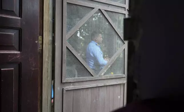 A state-assigned bodyguard for the family of slain environmentalist Juan López stands watch outside their home in Tocoa, Honduras, Friday, Dec. 6, 2024. (AP Photo/Moises Castillo)