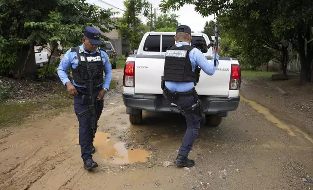 State-assigned bodyguards escort Thelma Peña and her daughter Julia, family members of slain environmentalist Juan López, out of their house in Tocoa, Honduras, Friday, Dec. 6, 2024. (AP Photo/Moises Castillo)