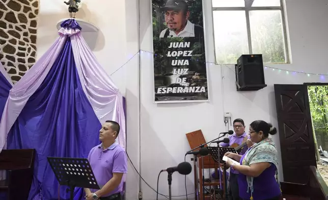 A poster of slain environmentalist Juan Lopez hangs on a wall at the San Isidro Labrador church during a Mass in Tocoa, Honduras, Sunday, Dec. 8, 2024. (AP Photo/Moises Castillo)