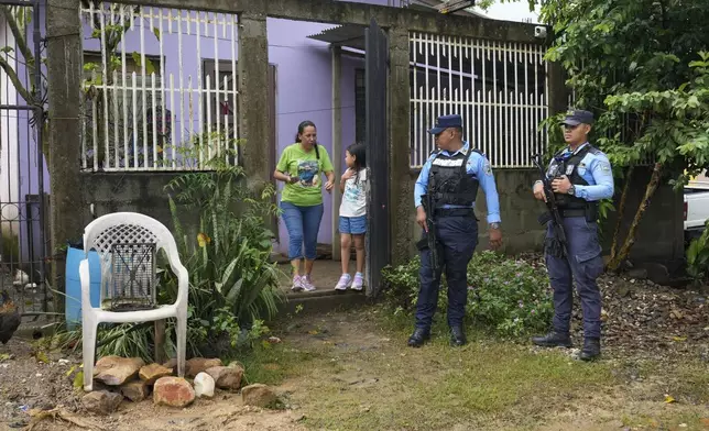 State-assigned bodyguards stand guard as Thelma Peña and her daughter Julia, family of slain environmentalist Juan López, leave their house in Tocoa, Honduras, Friday, Dec. 6, 2024. (AP Photo/Moises Castillo)