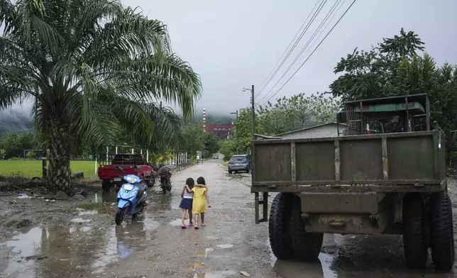 Residents walk through a street in the Lempira settlement, situated next to Los Pinares iron oxide mining project in Tocoa, Honduras, Saturday, Dec. 7, 2024. (AP Photo/Moises Castillo)