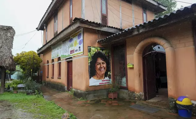 A banner of environmental leader Berta Cáceres, who was killed in 2016, hangs at the main entrance of the Municipal Committee for the Defense of the Common and Public Goods (CMDBCP) offices in Tocoa, Honduras, Thursday, Dec. 5, 2024. (AP Photo/Moises Castillo)