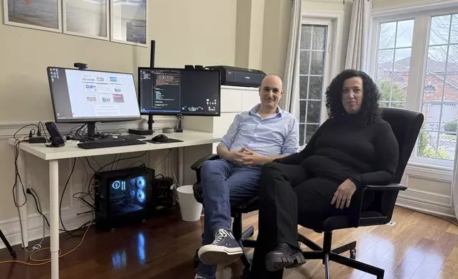 Michal Harel and her husband Avital Epstein show the website they set up to help Israelis navigate a move to Canada in Oakville, Ontario, Canada, Wednesday, Dec. 4, 2024. (AP Photo/Rob Gillies)