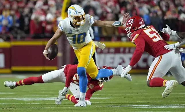 Los Angeles Chargers quarterback Justin Herbert (10) runs with the ball as Kansas City Chiefs safety Chamarri Conner (27) and defensive end Mike Danna (51) defend during the first half of an NFL football game Sunday, Dec. 8, 2024, in Kansas City, Mo. (AP Photo/Ed Zurga)