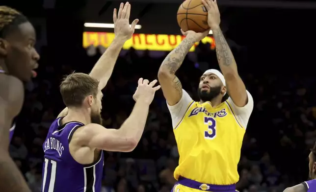 Los Angeles Lakers forward Anthony Davis (3) looks to shoot against Sacramento Kings center Domantas Sabonis (11) during the first half of an NBA basketball game in Sacramento, Calif., Thursday, Dec. 19, 2024. (AP Photo/Jed Jacobsohn)