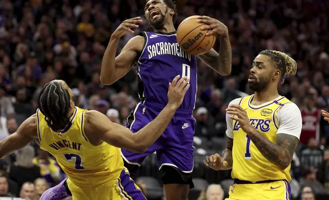 Sacramento Kings guard Malik Monk (0) is defended by Los Angeles Lakers guards Gabe Vincent (7) and D'Angelo Russell (1) during the second half of an NBA basketball game in Sacramento, Calif., Thursday, Dec. 19, 2024. (AP Photo/Jed Jacobsohn)