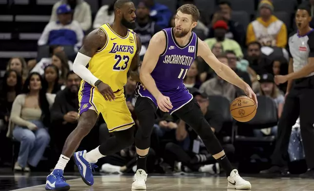 Los Angeles Lakers forward LeBron James (23) defends against Sacramento Kings center Domantas Sabonis (11) during the first half of an NBA basketball game in Sacramento, Calif., Thursday, Dec. 19, 2024. (AP Photo/Jed Jacobsohn)